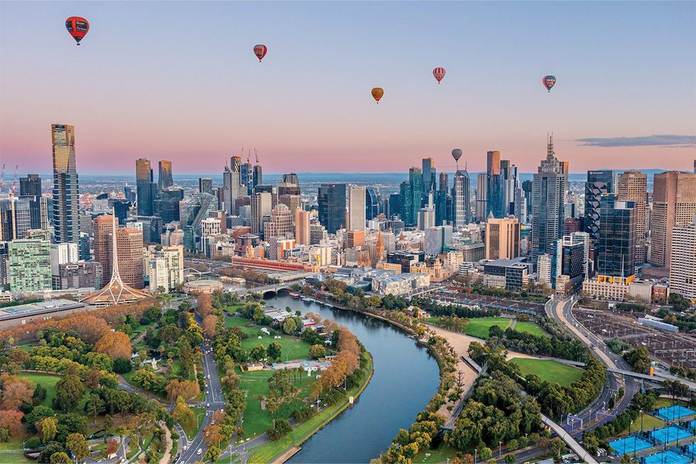 How Melbourne’s AI and Data Center Flywheel Is Accelerating Research Innovation Hot-air balloons over a riverside city skyline at sunrise with parks in the foreground