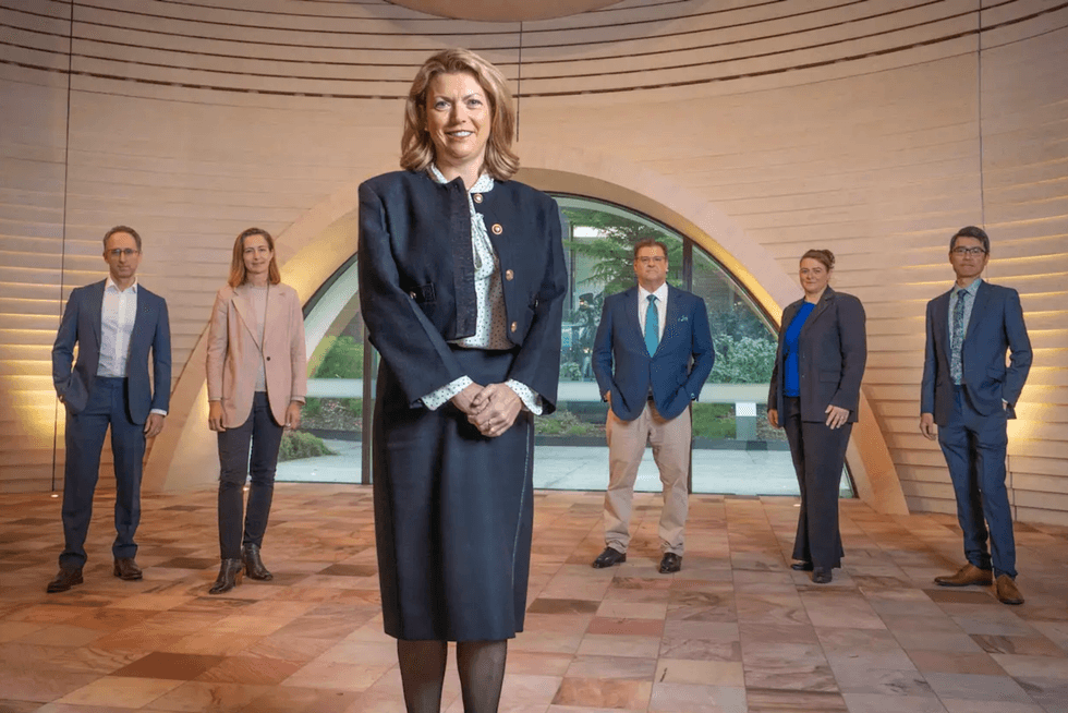 Professionals in business attire stand in a modern, arched lobby formation.