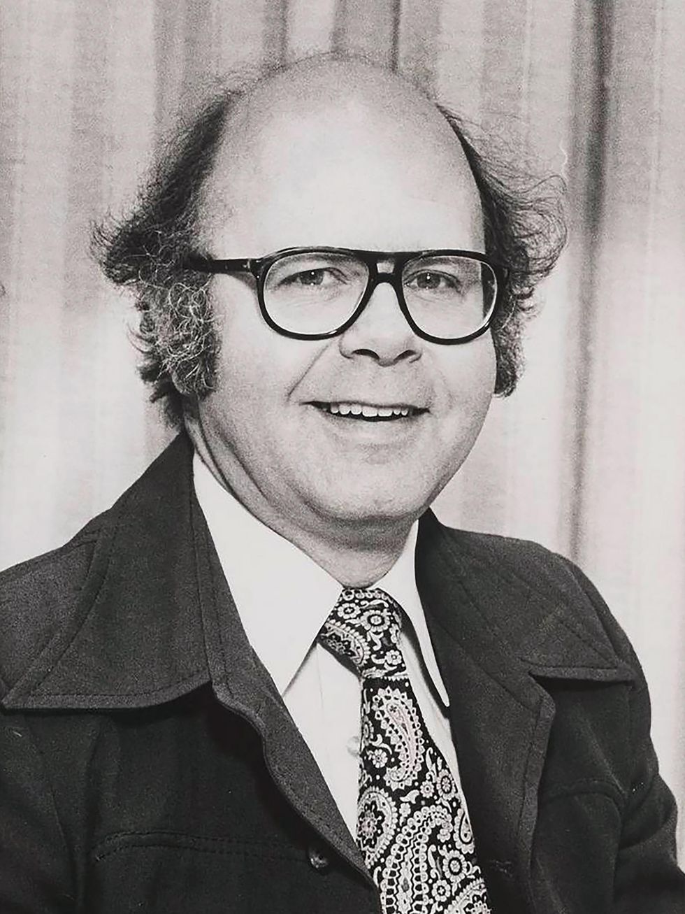 Black-and-white portrait of a middle-aged balding man in aviator eyeglasses.