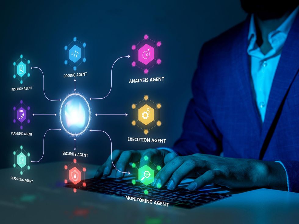AME Agent Swarms Quietly Rewrite the Workflow Person typing on a keyboard. Looming in front of them is a network of colorful AI agents surrounding a glowing central node.