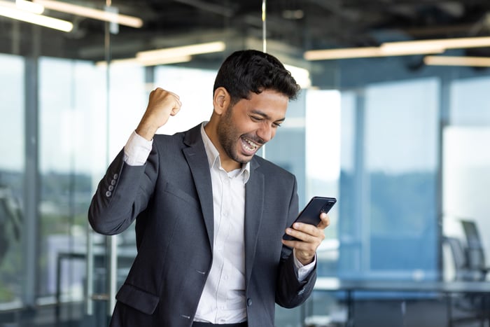 Here’s the 1 Habit That Has Helped Ordinary Investors Build Extraordinary Wealth in the Stock Market An excited and happy person is waving their fist and looking at a phone.